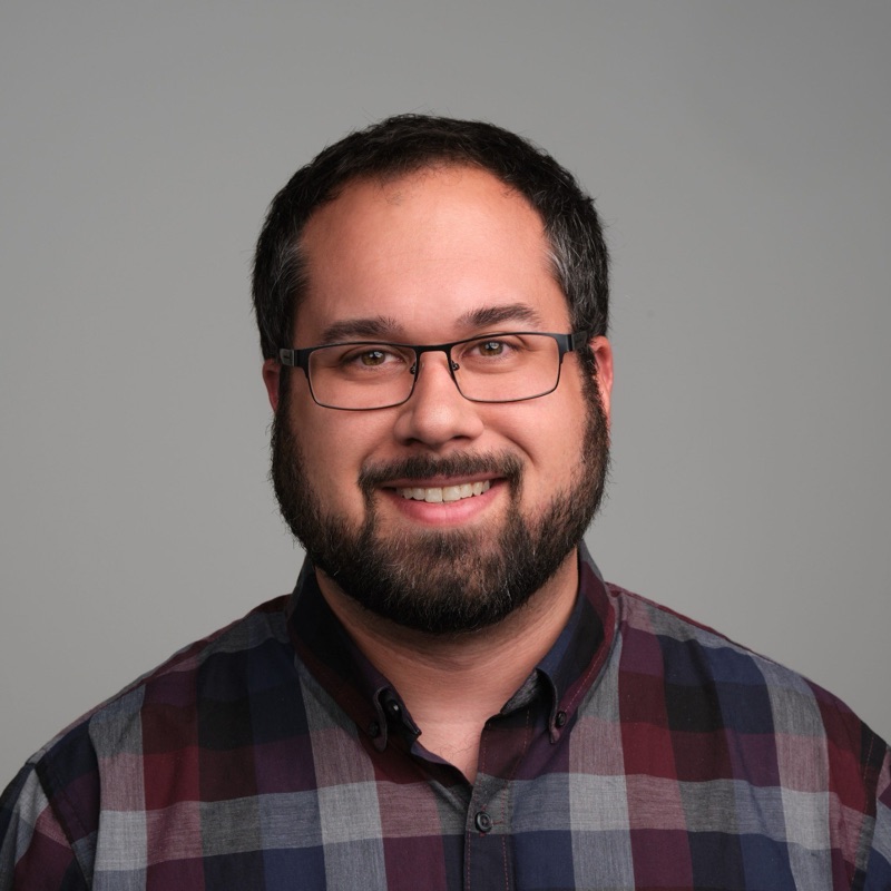 Allen Jones, smiling, wearing glasses and a plaid shirt